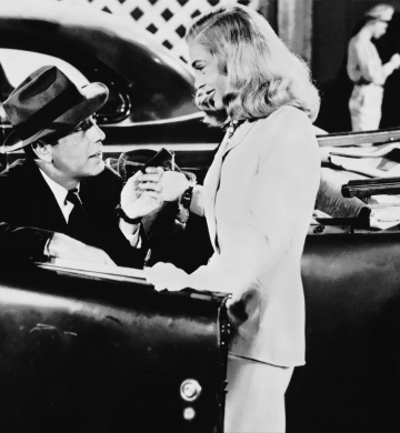 A man sitting in a car is talking to a woman who is smiling at him